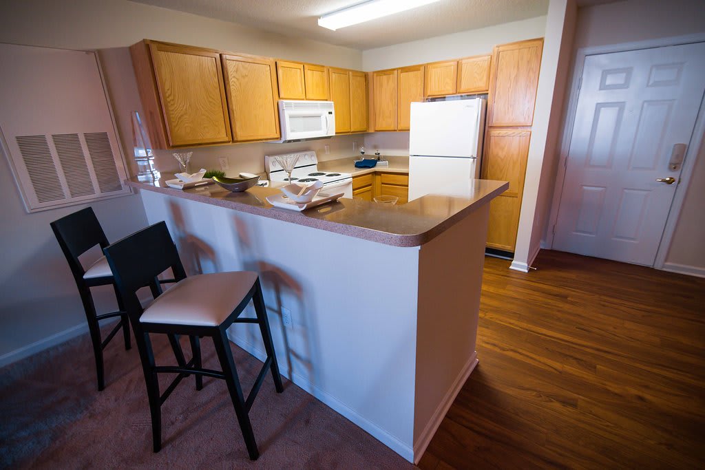 Legacy at Friendly Manor kitchen with white refrigerator and wood cabinets - Greensboro, NC
