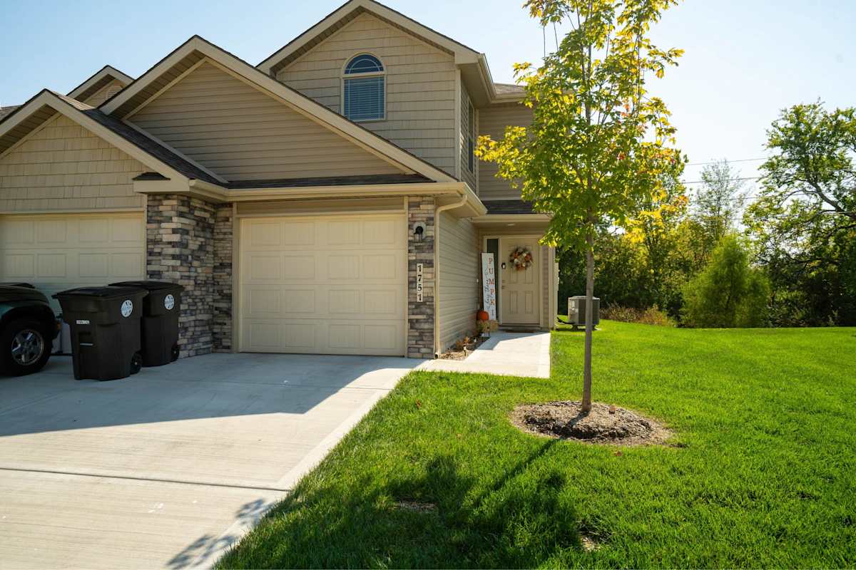 Traditions Townhomes exterior with attached garages and driveway - Belton, MO