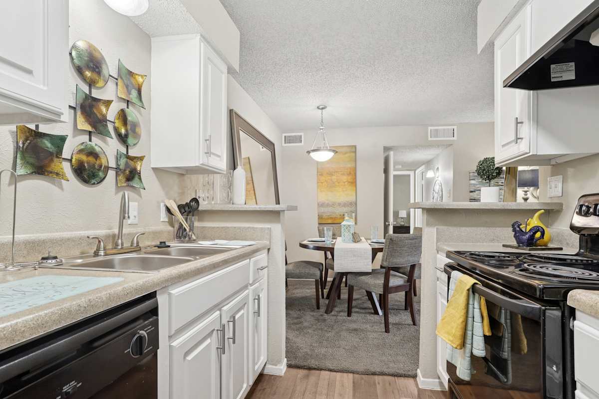 The Venue at Greenville unit kitchen with white cabinets and black range - Dallas, TX