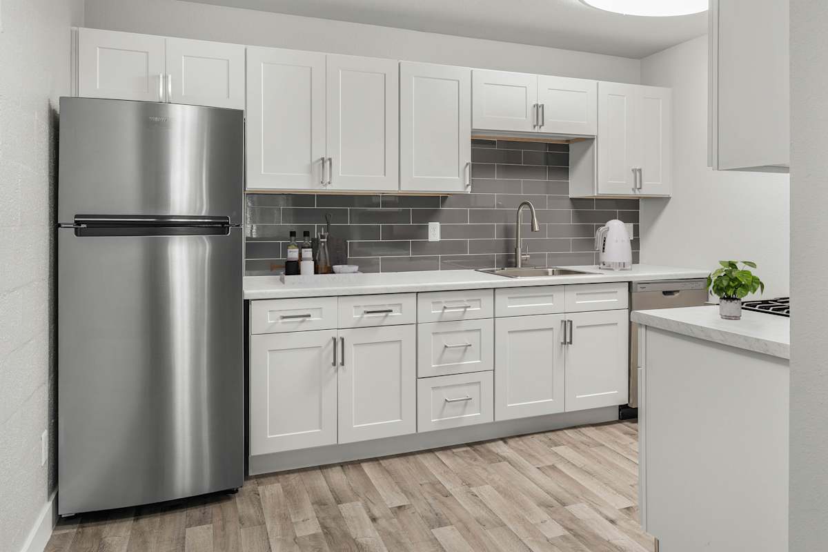 2025 West Apartment Homes modern kitchen with stainless steel refrigerator and white cabinets - Phoenix, AZ