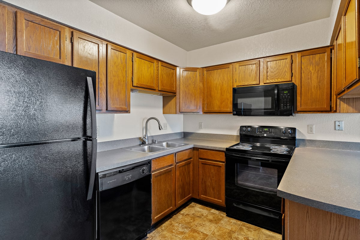 Olympic Village Apartments kitchen with dark appliances - Billings, MT