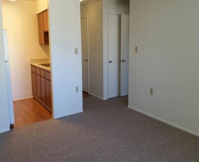 Unfurnished room with closet doors and adjoining kitchenette — view 1 at Kachina Place.