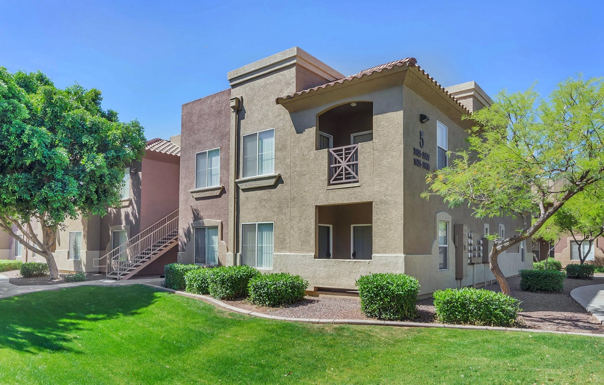 Apartment exterior with upper-floor balconies and landscaped lawn.