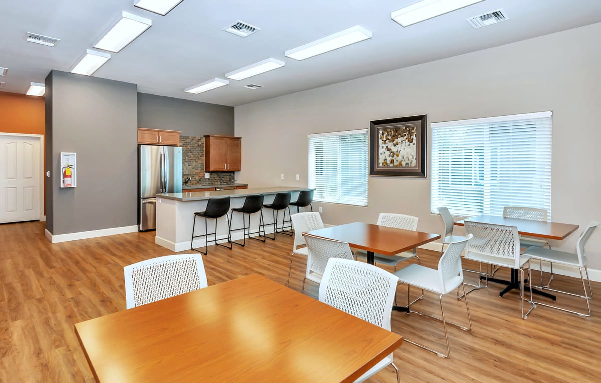 Activity room with tables beside a shared kitchen.
