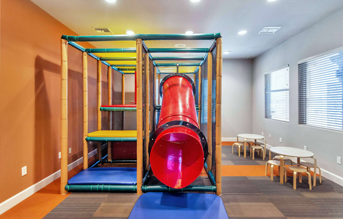 Indoor play area with climbing structure and red slide.