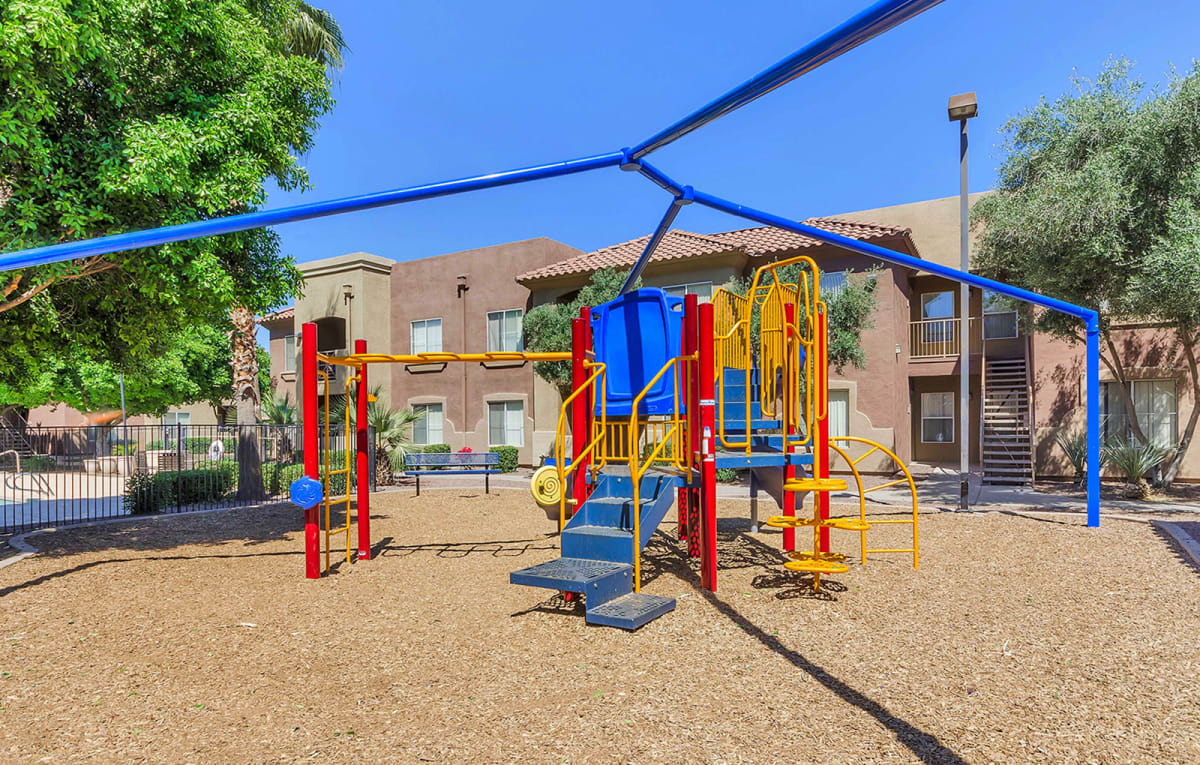Playground climbing equipment beneath shade supports.