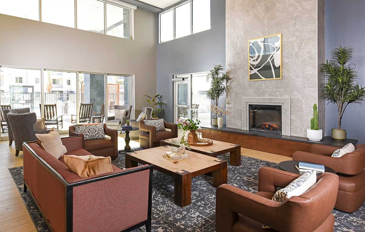Shared clubhouse lounge with tall windows and seating — view 1 at Juniper Square 55+ Apartments.