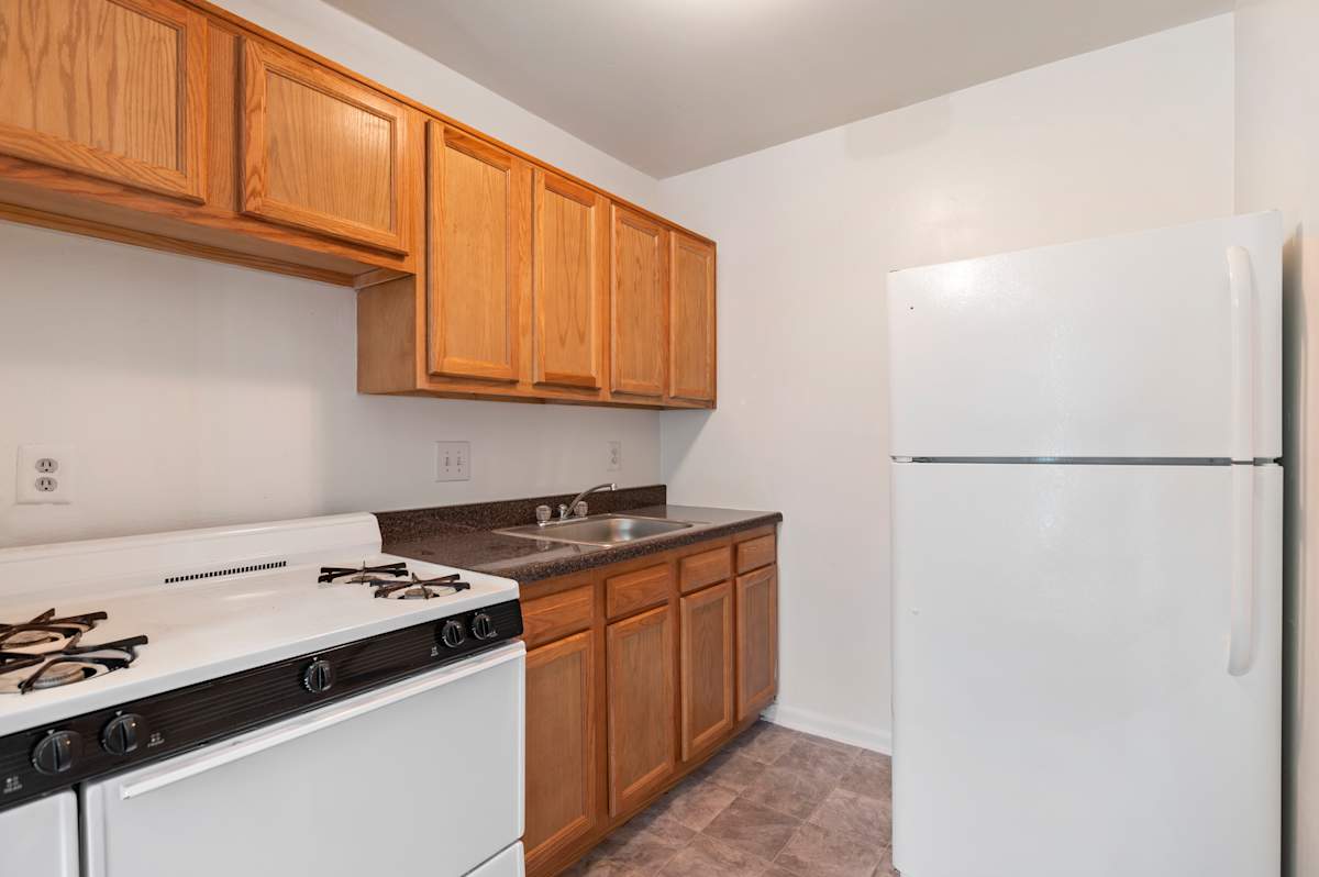 Park Pleasant Apartments kitchen with white appliances and wood cabinets - Washington, DC