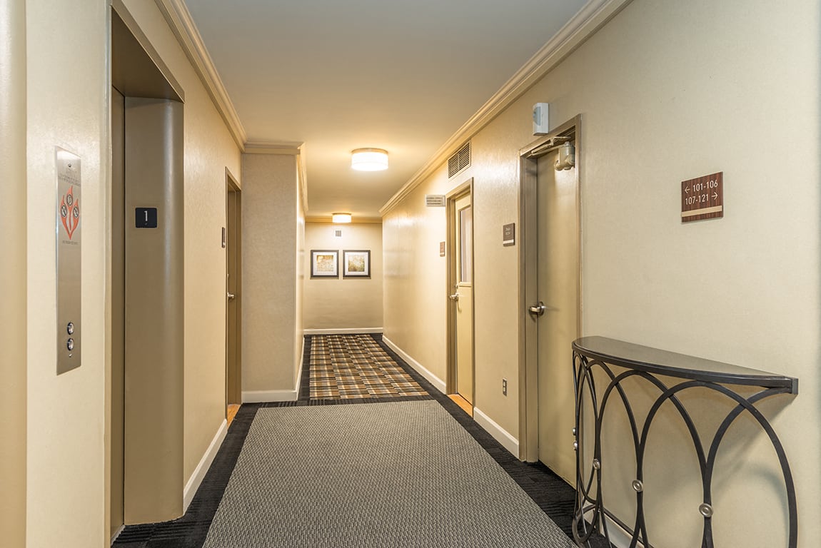 The 925 Apartments hallway with elevator and patterned carpet - Washington, DC