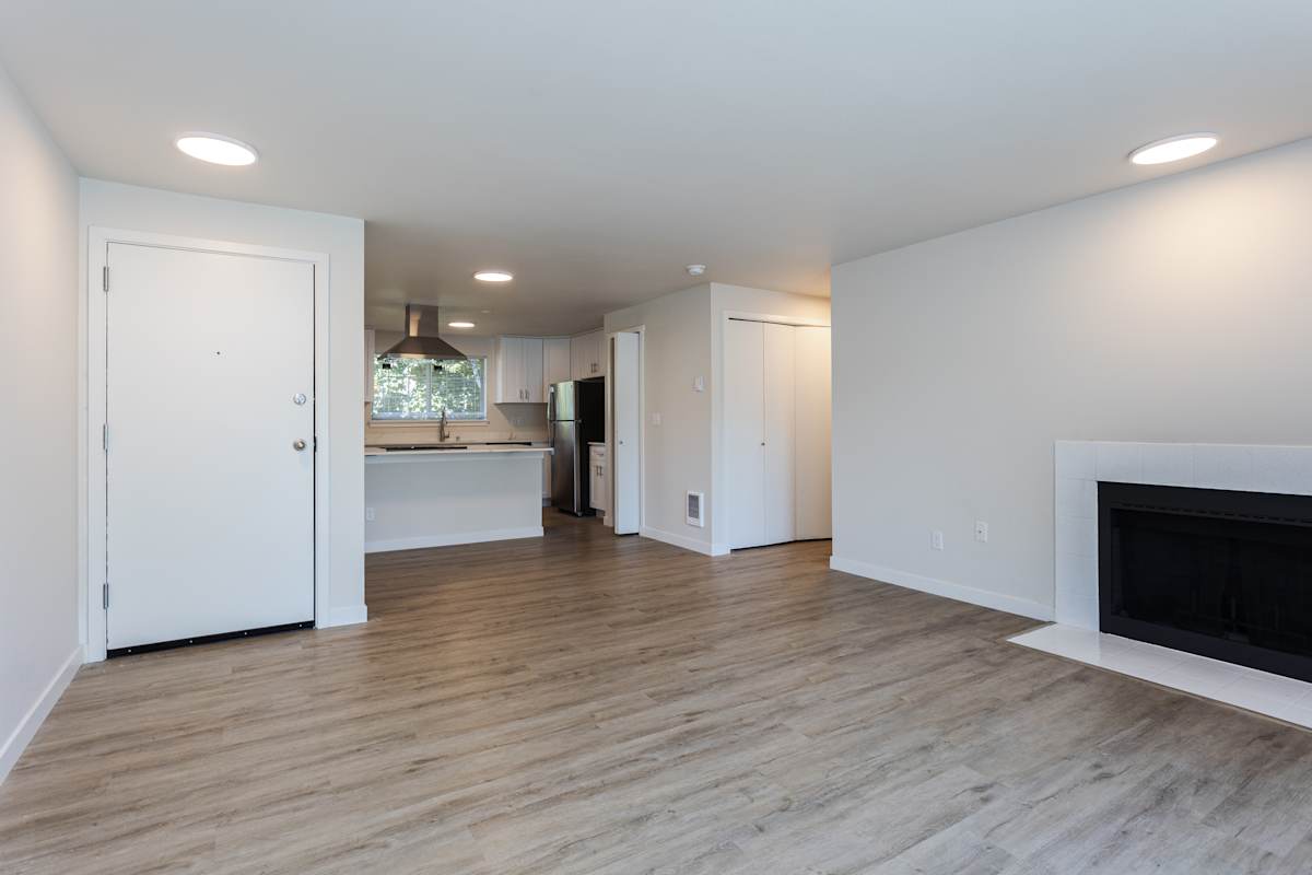 Ellyson Apartment Homes living room with fireplace and kitchen view - Tacoma, WA