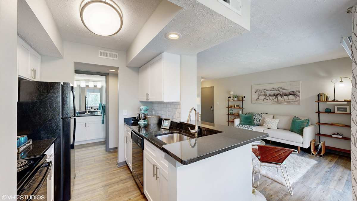 Runaway Bay Apartments kitchen and living area with dark countertop - Columbus, OH
