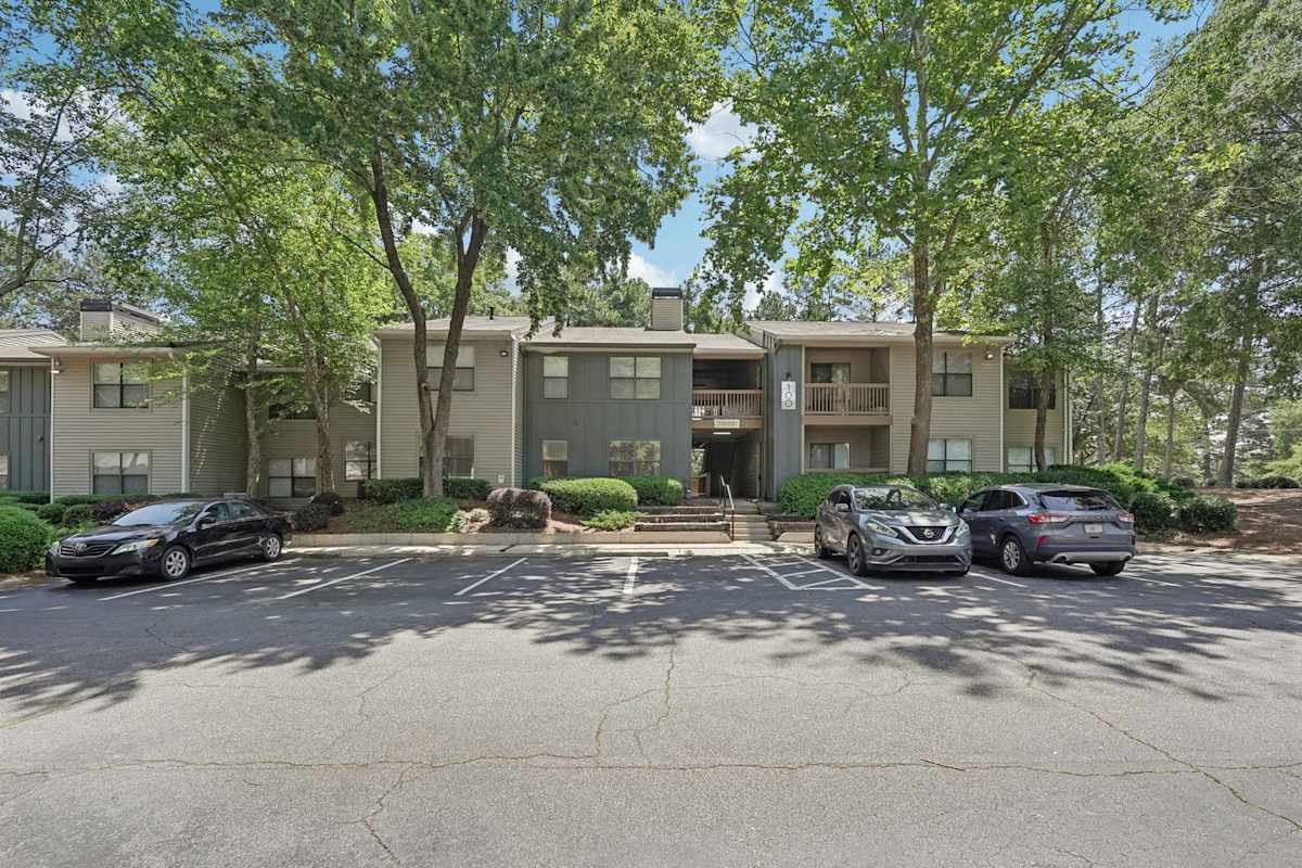Wesley Trevento Apartments at Lithia Springs apartment building with trees and parking lot - Lithia Springs, GA