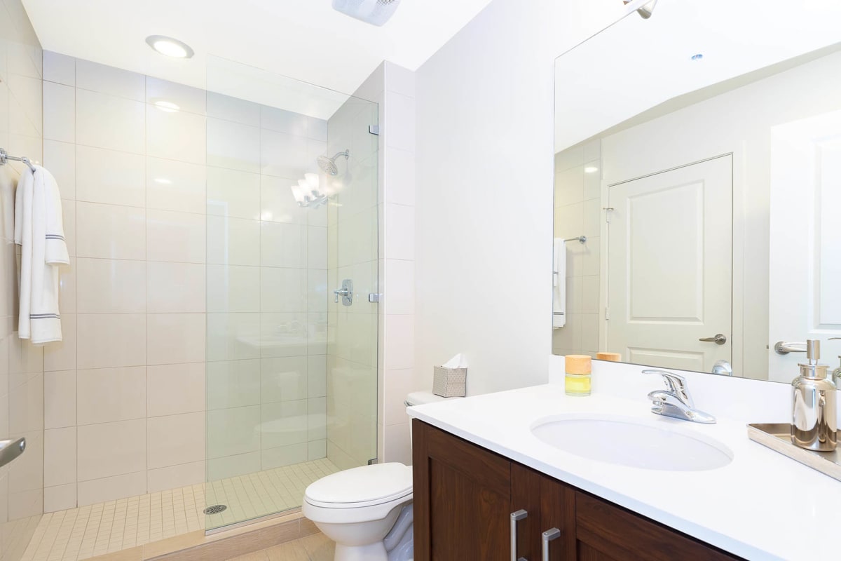 NORA Apartments bathroom with vanity and glass shower divider - Orlando, FL