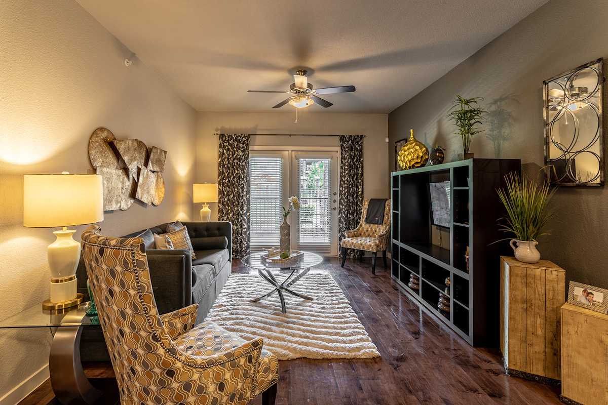 Verandas at Alamo Ranch living area with ceiling fan and balcony door - San Antonio, TX