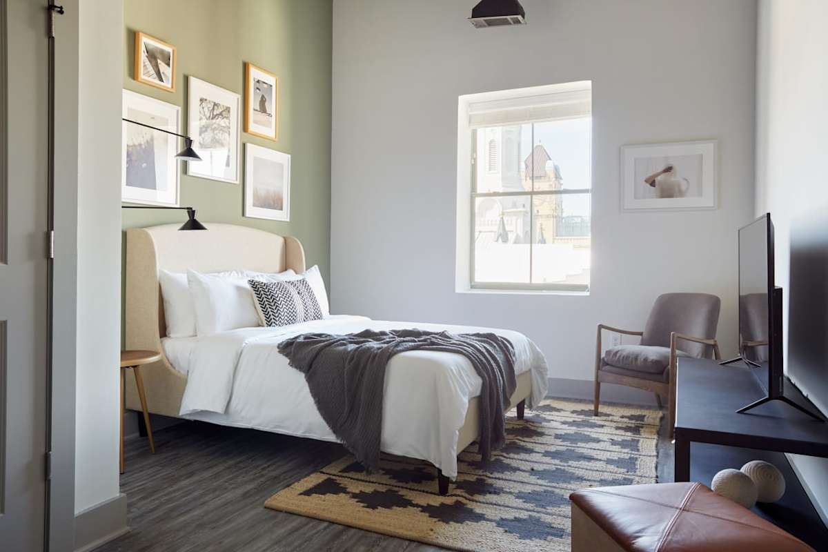 Capital Bull Apartments bedroom with bed and chair - Savannah, GA