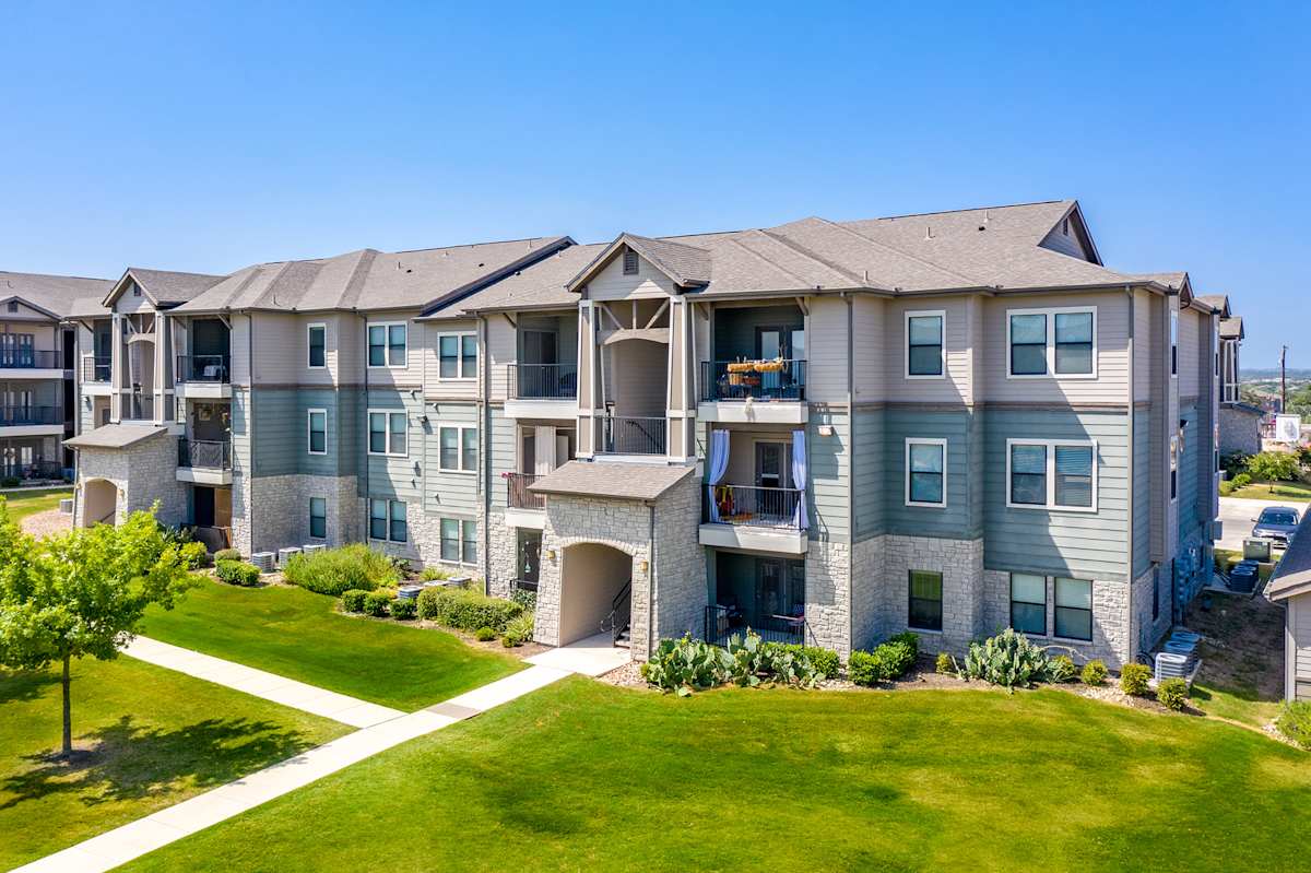 Verandas at Alamo Ranch apartment exterior with green lawns - San Antonio, TX