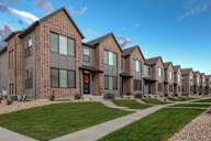 A row of modern brick houses with green lawns in front.