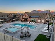 A large outdoor swimming pool with a striped umbrella and lounge chairs.