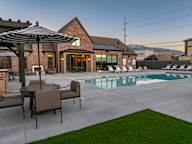 A patio with a table and chairs and an umbrella is in front of a house.