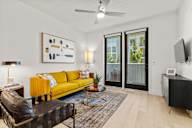 Luxury Apartments for Rent in Sacramento, CA - The Eisley - Spacious Living Room with Wood-Inspired Plank Flooring, a Ceiling Fan, Yellow Couch, Round Coffee Table with Access to a Private Balcony