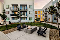 Luxury Apartments for Rent in Sacramento, CA - The Eisley - Firepit with Outdoor Furniture, Manicured Lawn, and View of Apartment Complex