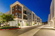 a large apartment building at night with the street in front of it