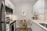 an apartment kitchen with stainless steel appliances and white cabinets