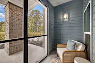 a screened porch with a couch and a table and a brick wall