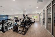 a row of treadmills in a fitness room with glass doors