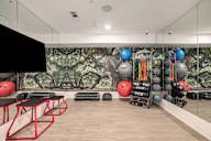 a fitness room with a wall mural of a forest with spheres and balls