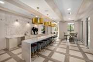 a large kitchen with a long counter and chairs and a dining table