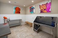 A room with a bench, a table, and two paintings on the wall.