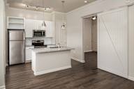 A kitchen with a refrigerator, microwave, and oven.