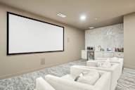 A modern living room with a large screen and comfortable seating.