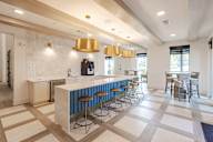 A kitchen with a white counter and blue bar stools.