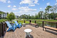 a deck with chairs and a table overlooking a body of water