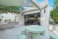 A white table and two stools are in front of a glass door. at The Viridian, Scottsdale, AZ
