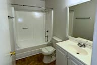 A white bathroom with a toilet, sink, and shower.
