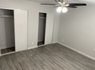 A room with a ceiling fan and three closets.