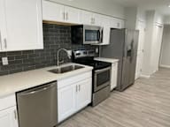 A kitchen with white cabinets and a black backsplash.