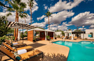 A pool area with a sun lounger and a striped umbrella.