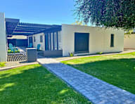 A modern house with a white exterior and a grey walkway leading to the front door.