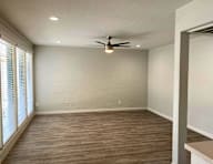 A room with a ceiling fan and wooden flooring.