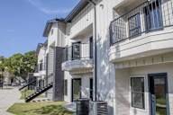 A modern two-story apartment building with a balcony on the second floor.