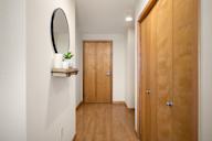 a hallway with a wooden door and a mirror on the wall at Verge Apartments in St. Louis Park, MN