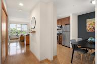 a dining room with a table and chairs and a kitchen with stainless steel appliances at Verge Apartments in St. Louis Park, MN