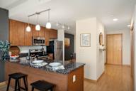 a kitchen with a granite counter top and a stainless steel refrigerator at Verge Apartments in St. Louis Park, MN