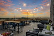 A rooftop patio with a table, chairs, and string lights.