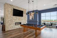 a games room with a pool table and a fireplace at Verge Apartments in St. Louis Park, MN