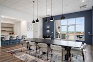 a dining room with a black table and chairs and a kitchen with a large window at Verge Apartments in St. Louis Park, MN